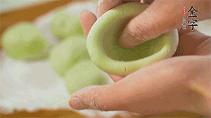 將均分的艾草面團搓成圓，挖一個窩，放入餡心，再搓成圓。