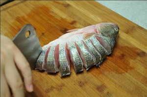將鱸魚(yú)清洗干凈，從脊椎處切斷至腹部，腹部保留1cm左右不要切斷。