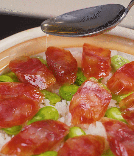 大米出現(xiàn)小孔時(shí)開蓋放香腸，往鍋邊淋入少許油，再燜煮8~10分鐘左右。